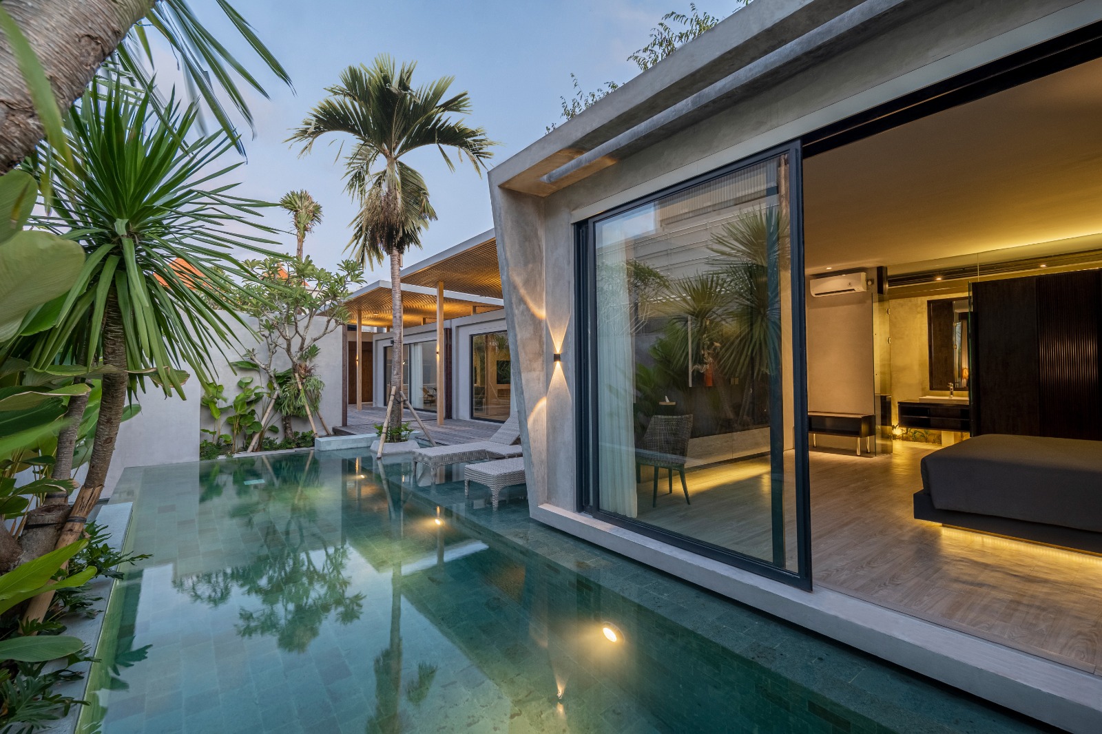 Luxurious modern villa with a lavish pool surrounded by palm trees by Inspira Seminyak Villas