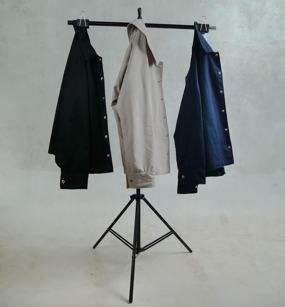 Three men's jackets in different colors hanging on a standing clothes hanger
