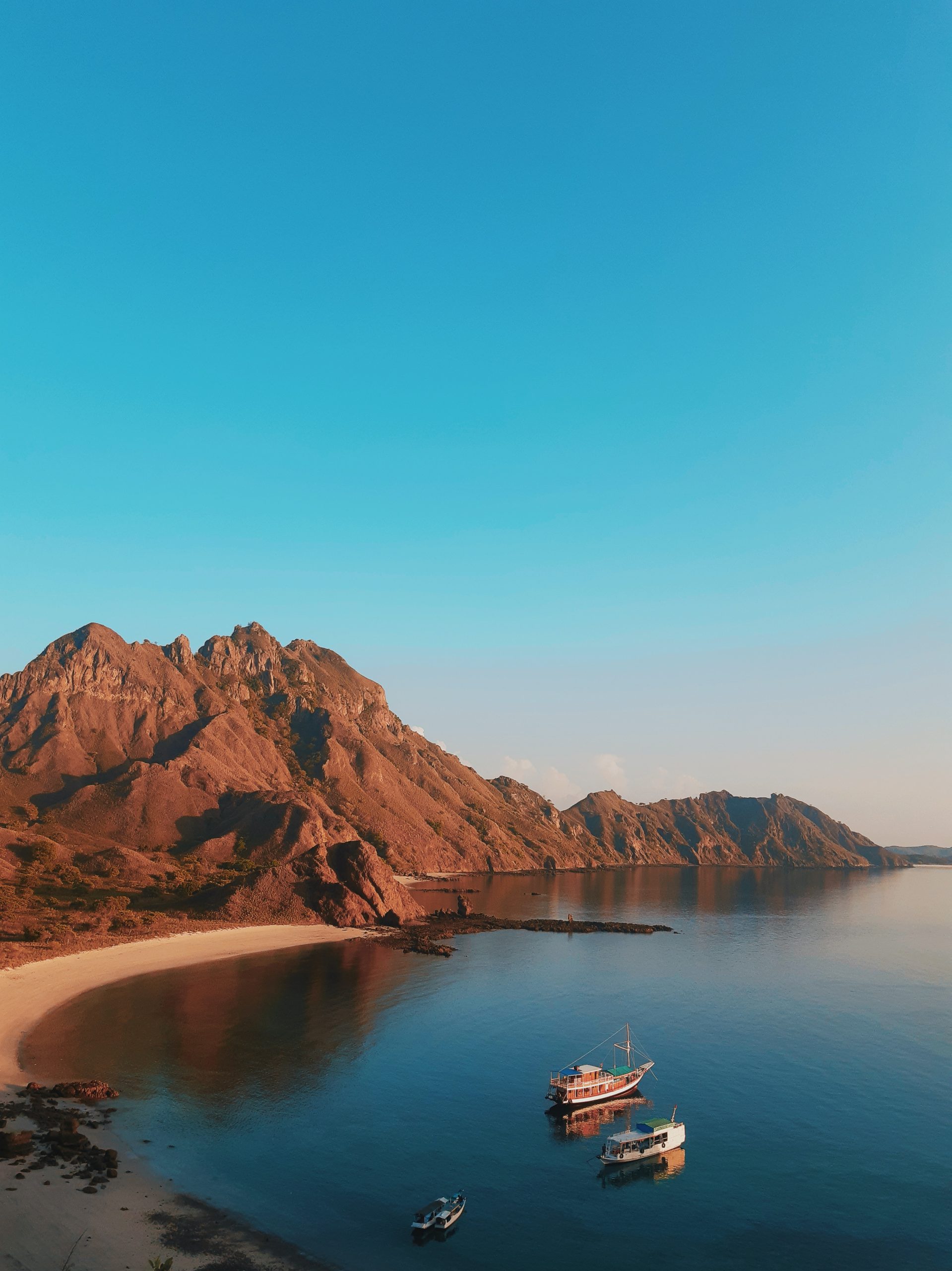 Beautiful Labuan Bajo ocean surrounded by majestic hills and three boats