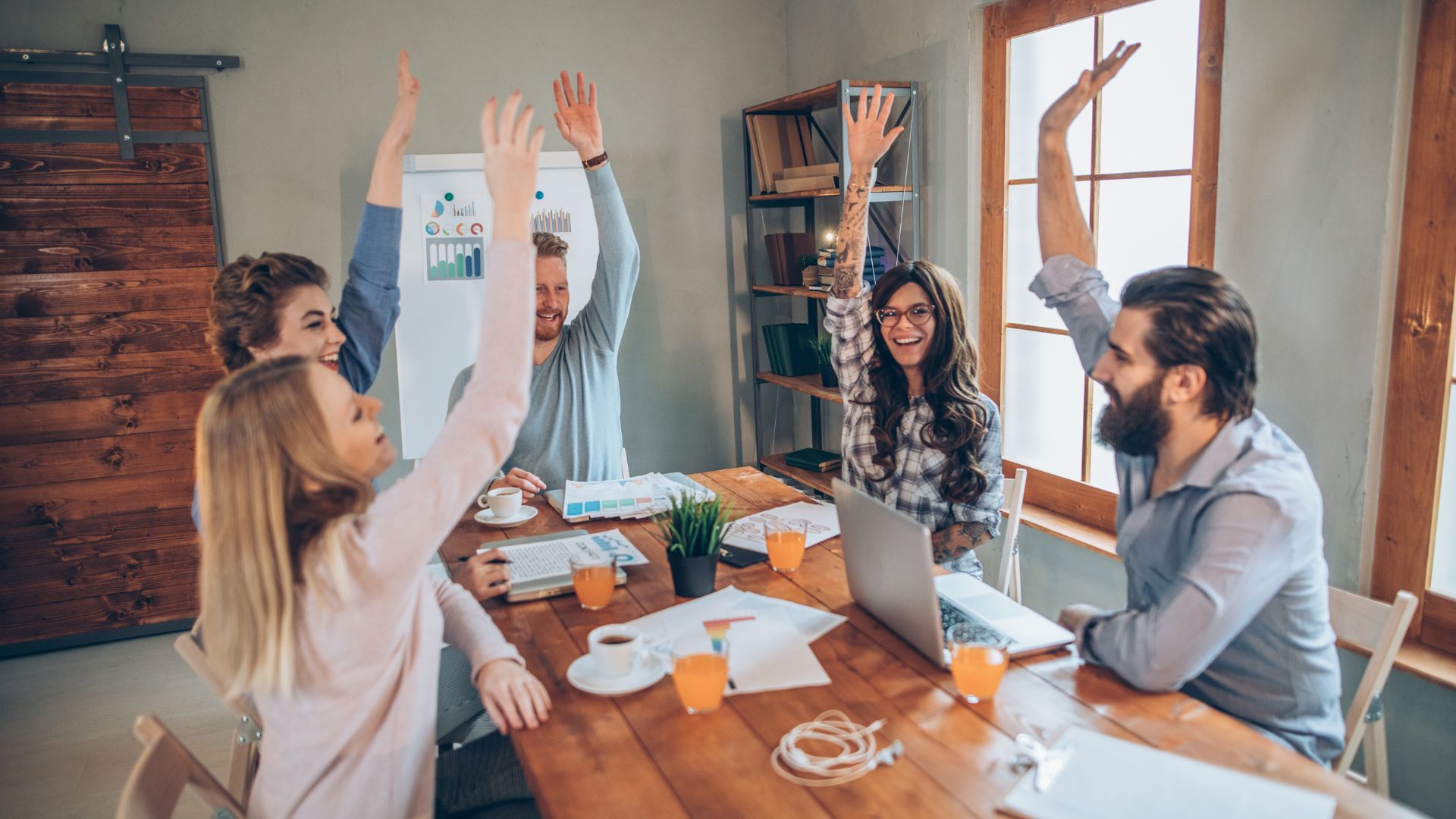 A team of five advertising analysis members joyfully celebrating the success of their campaign.