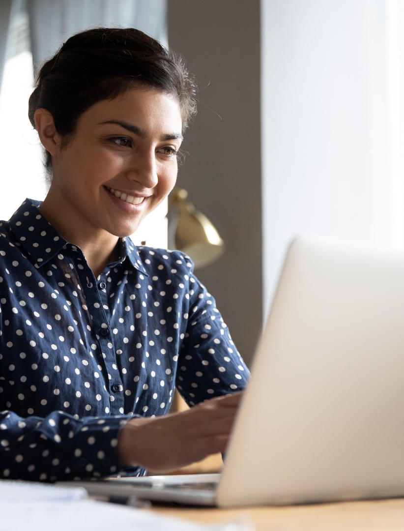 Turkish-or-Indian-female-model-in-polkadot-dark-blue-shirt-smile-look-at-her-phone-while-typing-the-email-follow-up-to-her-hotel-clients