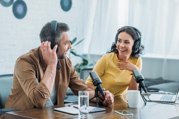 Male and female podcasters recording a podcast in a studio