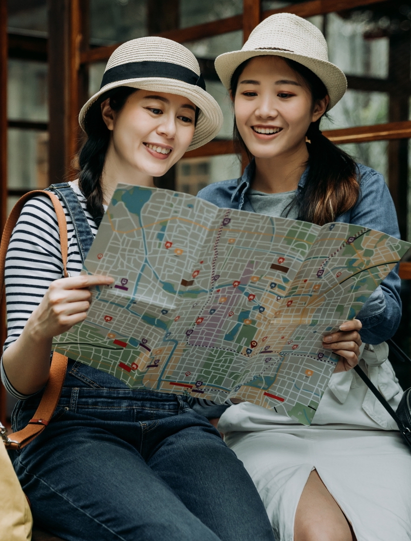 two-girls-traveller-with-white-hat-look-at-the-map-that-provide-by-travel-management-guide-company