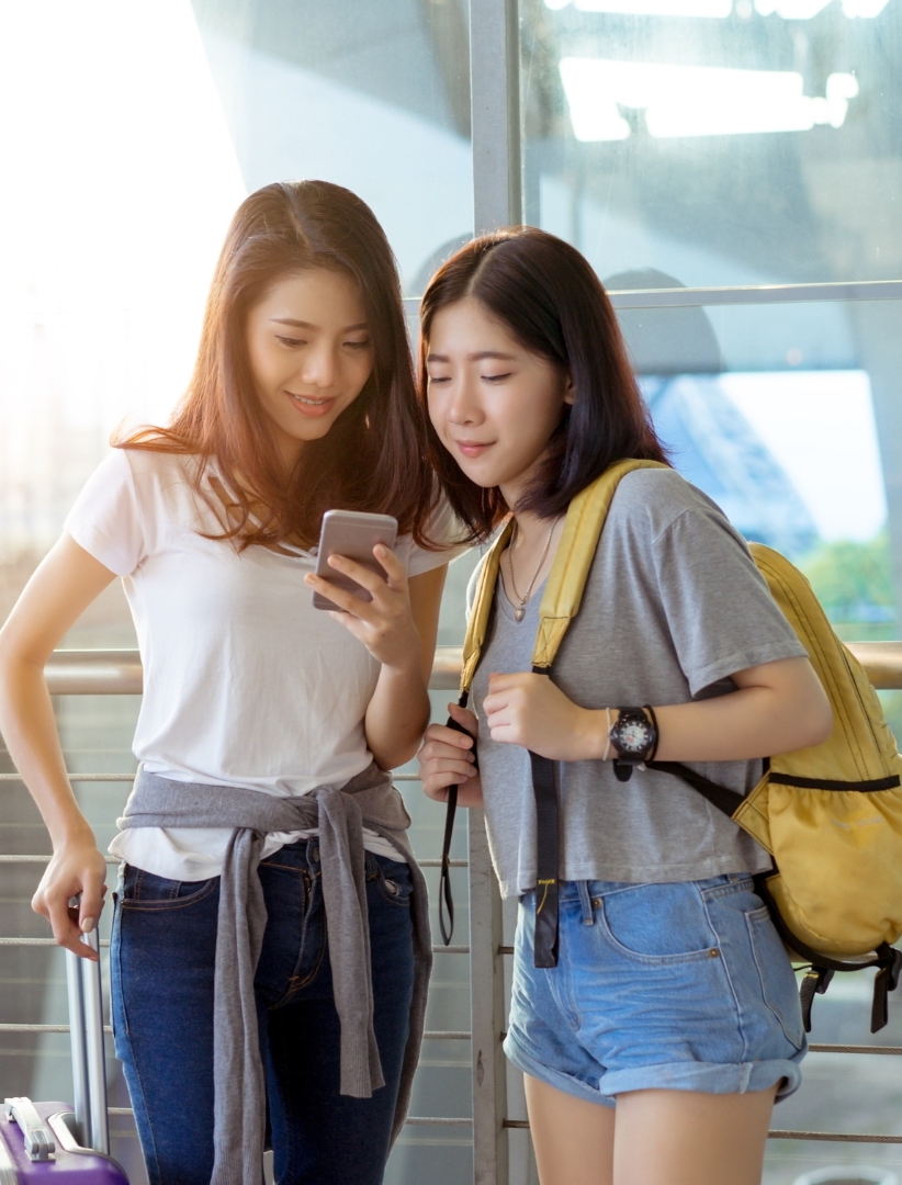 two-young-girls-with-traveling-attributes-in-the-airport-discuss-about-choosing-a-business-travel-booking