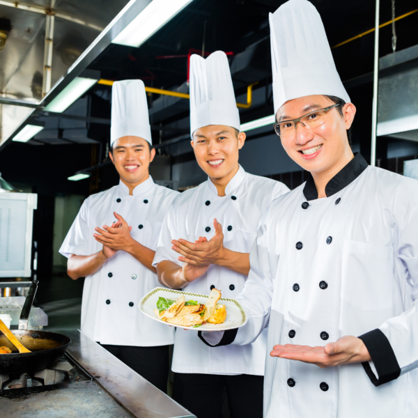 three male hotel chefs are cooking preparing food in accordance with food and beverage trends in hospitality industry in the kitchen of a five-star hotel in Bali